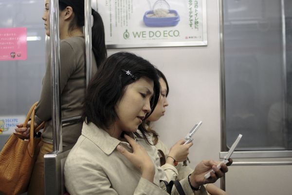 زن ژاپنی در مترو در حال استفاده از موبایل